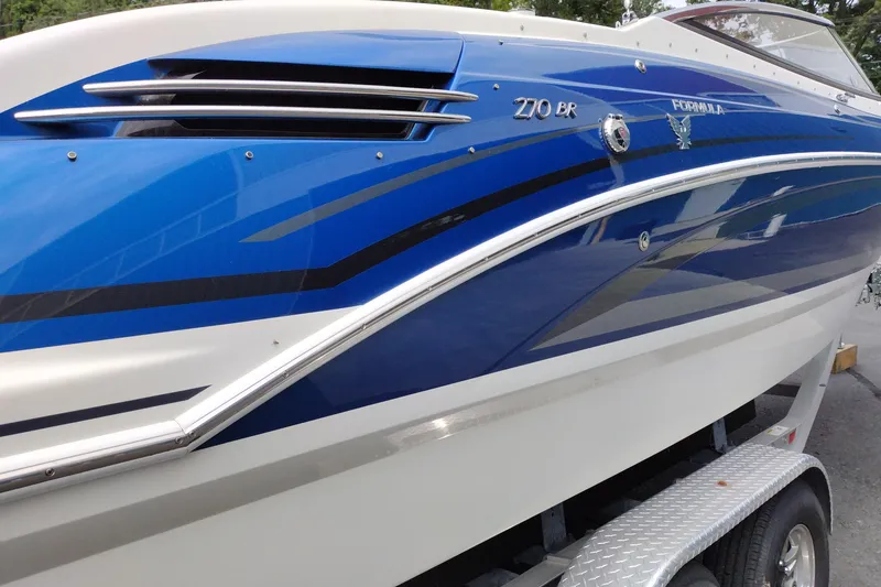 Slide: The Image of 2016 Formula 270 Bowrider boat with sleek blue and white design on a trailer. - 6