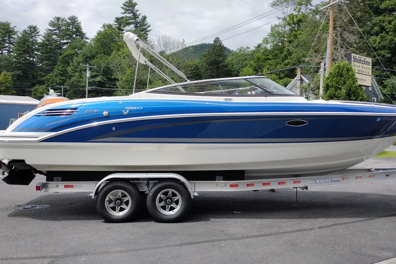 Slide: The Image of 2016 Formula 270 Bowrider boat on trailer, parked outdoors with trees in background. - 7