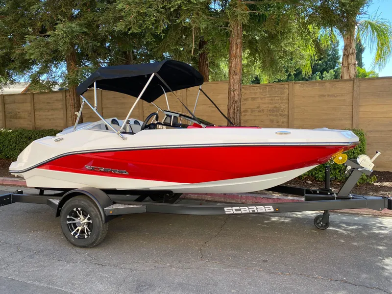 Slide: The Image of 2025 Scarab 165 SE boat with red and white design on a trailer. - 1