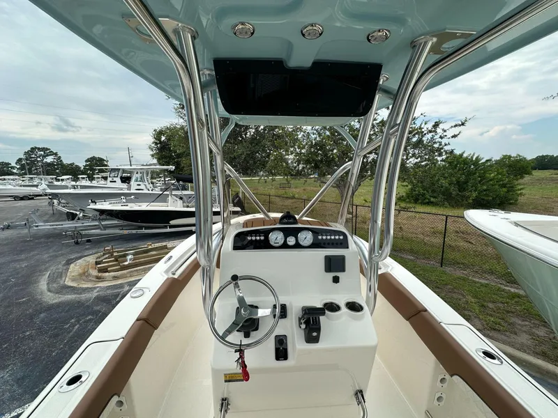 Slide: The Image of 2025 Pioneer 202 Islander boat console with steering wheel and controls, docked outdoors. - 4