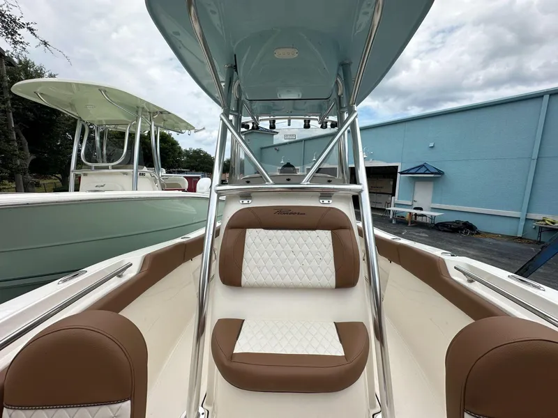 Slide: The Image of 2025 Pioneer 202 Islander boat interior with brown and white seating, under a cloudy sky. - 6