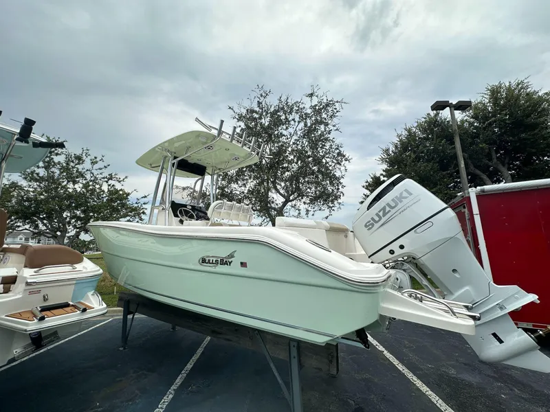 Slide: The Image of 2025 Bulls Bay 230 CC boat with Suzuki outboard motor, parked outdoors. - 5