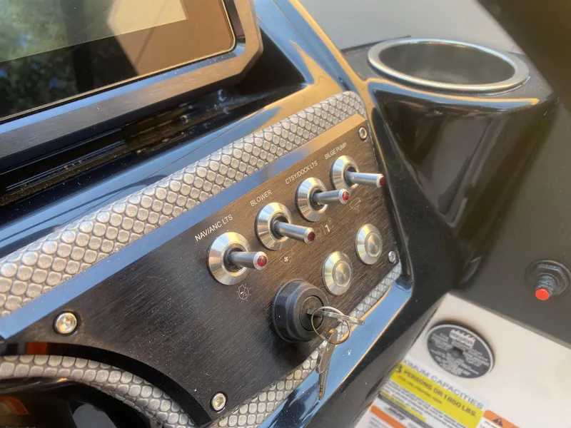 Slide: The Image of Dashboard controls of a 2025 Scarab 255 ID boat with ignition key. - 15