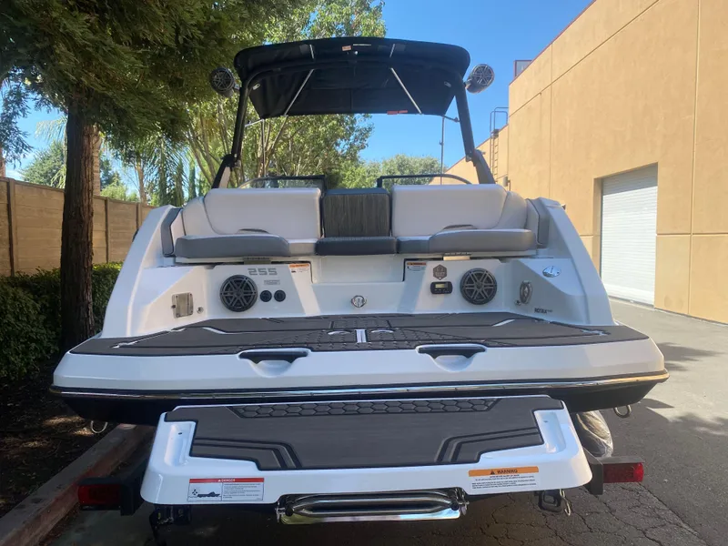 Slide: The Image of 2025 Scarab 255 ID boat, rear view, parked outdoors, showcasing seating and speakers. - 2
