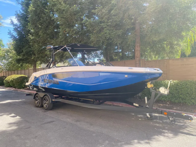 Slide: The Image of 2025 Scarab 255 ID boat on trailer, blue and white, parked outdoors. - 33