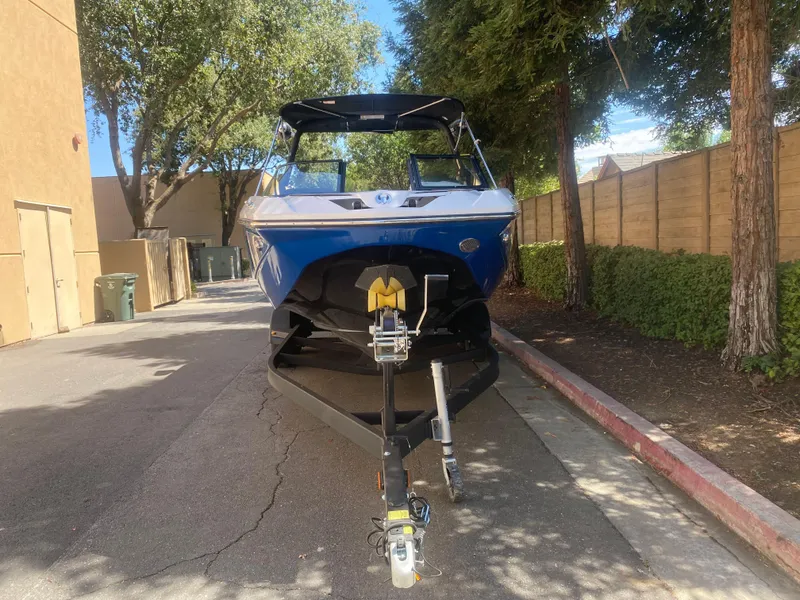 Slide: The Image of 2025 Scarab 255 ID boat on trailer, parked in a shaded driveway. - 5