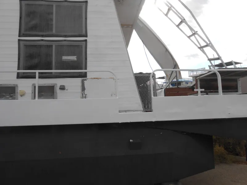 Slide: The Image of 1972 Boatel Hurcules houseboat with white exterior and large windows, docked outdoors. - 3