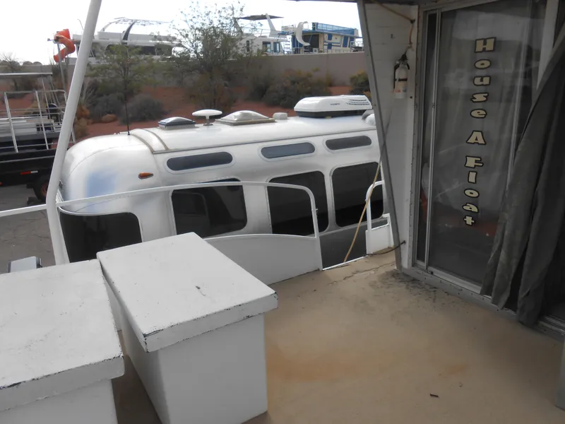 Slide: The Image of 1972 Boatel Hurcules houseboat with "House Afloat" sign, docked outdoors. - 8