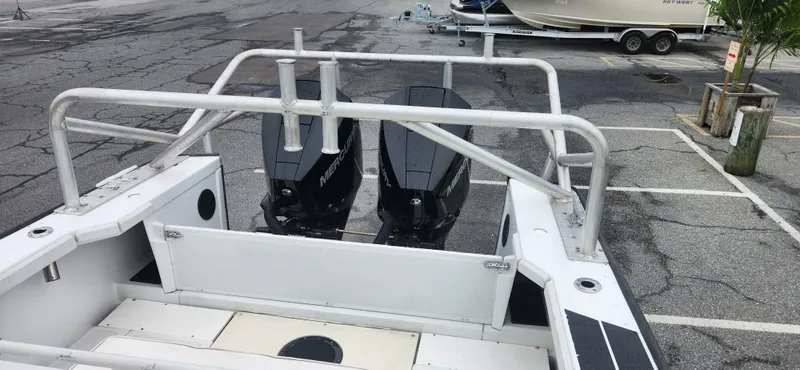 Slide: The Image of Boston Whaler Justice 24 boat, 2000 model, with dual outboard motors in a parking lot. - 15