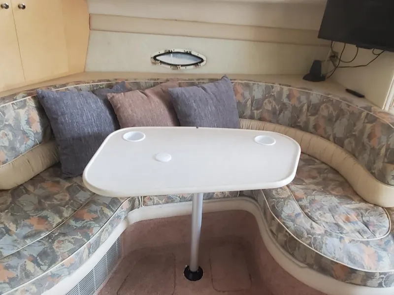 Slide: The Image of Interior of 2000 Bayliner 3055 Ciera Sunbridge with cushioned seating and table. - 13
