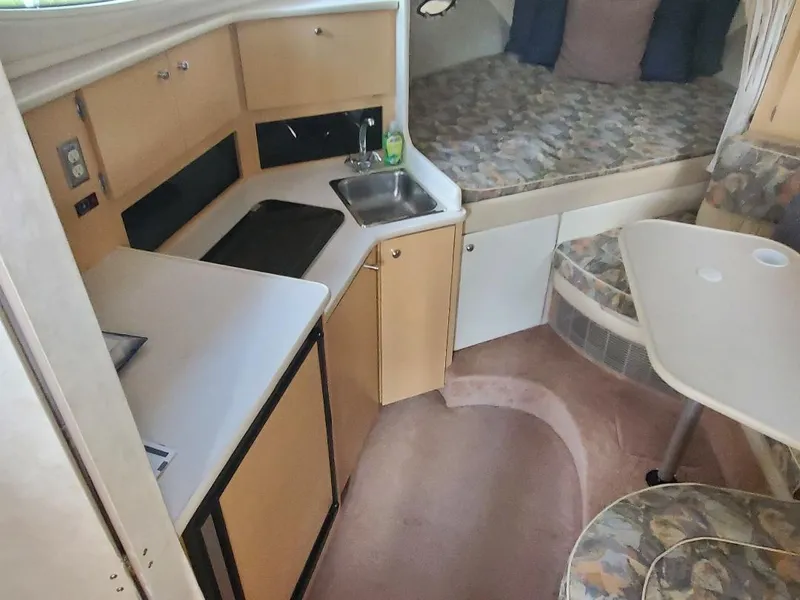 Slide: The Image of 2000 Bayliner 3055 Ciera Sunbridge DX/LX interior with kitchenette, seating, and sleeping area. - 5