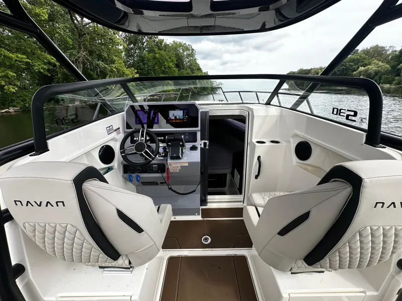 Slide: The Image of 2024 Navan S30 boat interior with modern dashboard and seating, cruising on a scenic river. - 26