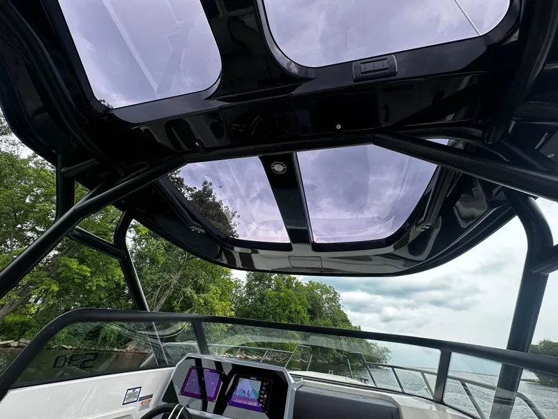 Slide: The Image of 2024 Navan S30 boat interior with panoramic sunroof and digital dashboard, cruising on a scenic waterway. - 30