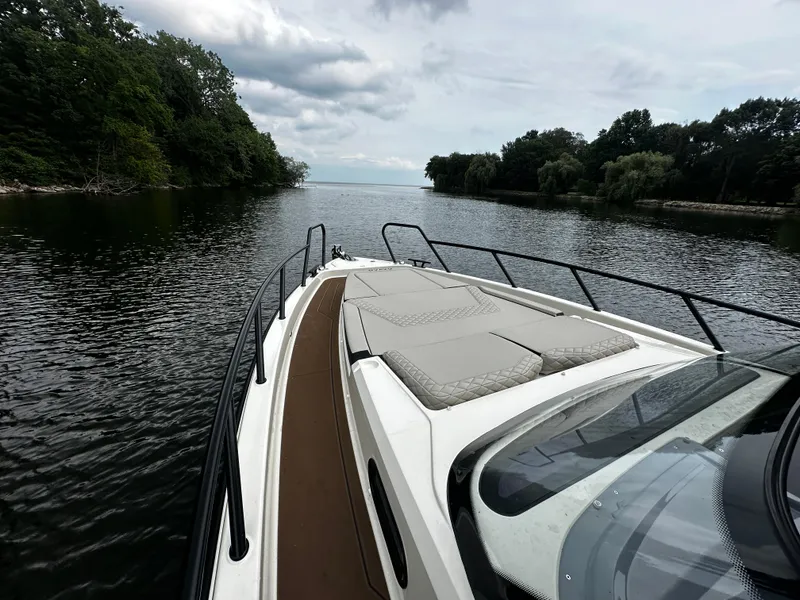 Slide: The Image of 2024 Navan S30 boat cruising on a serene lake with lush green shoreline. - 33