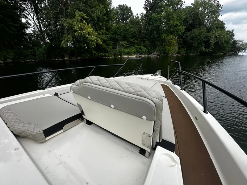 Slide: The Image of 2024 Navan S30 boat interior with cushioned seating, on a calm lake near lush greenery. - 39