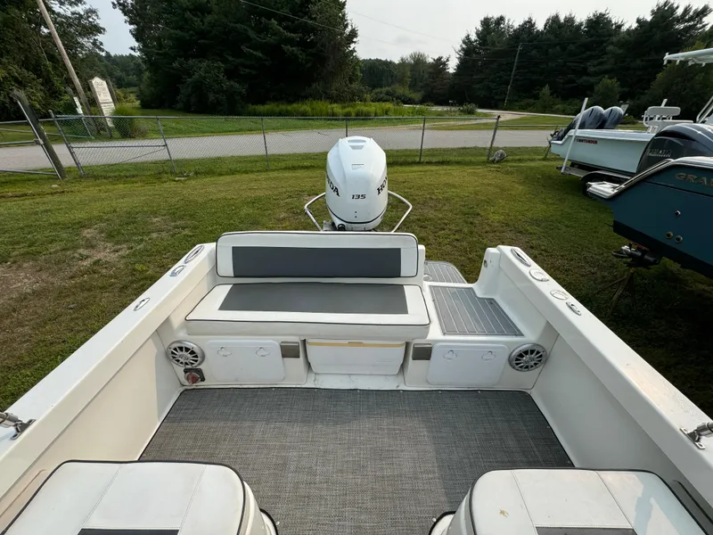 Slide: The Image of 2019 Eastern 21 Pilot boat interior with seating and outboard motor, parked on grass. - 11