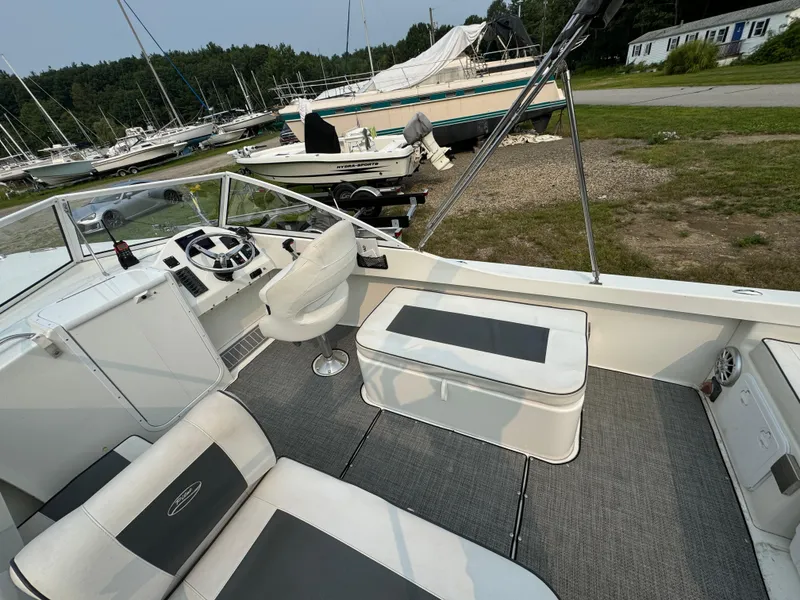 Slide: The Image of 2019 Eastern 21 Pilot boat interior with seating and steering wheel, docked near other boats. - 14