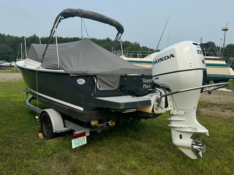 Slide: The Image of 2019 Eastern 21 Pilot boat with Honda outboard motor on a trailer, covered and parked on grass. - 4