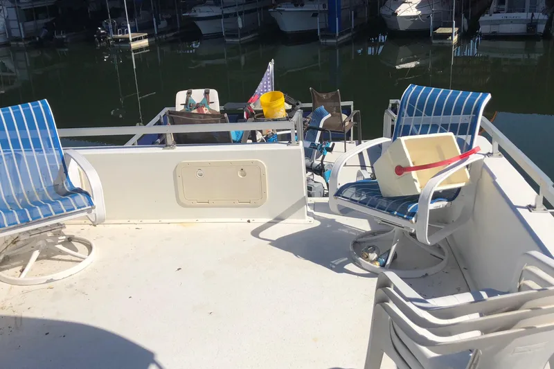 Slide: The Image of 1994 Gibson 50 Cabin Yacht deck with striped chairs and marina view. - 16