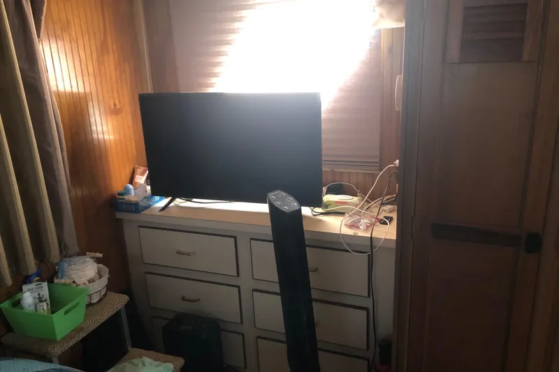 Slide: The Image of 1994 Gibson 50 Cabin Yacht interior with TV, drawers, and wooden paneling. - 33