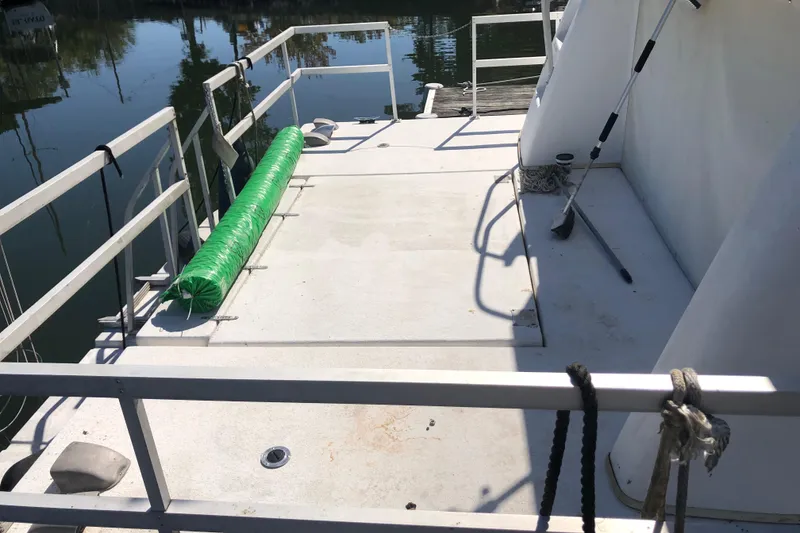 Slide: The Image of 1994 Gibson 50 Cabin Yacht deck with railing and green fender, docked by calm water. - 5