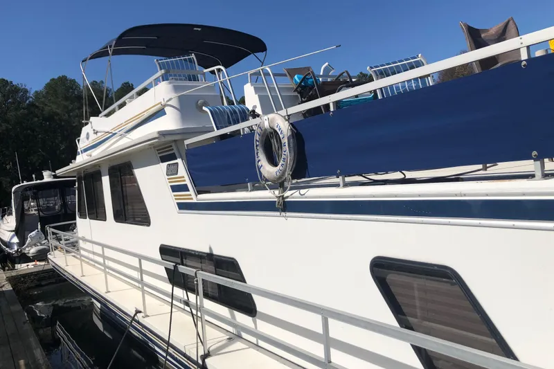 Slide: The Image of 1994 Gibson 50 Cabin Yacht docked, featuring upper deck and lifebuoy, under clear blue sky. - 8