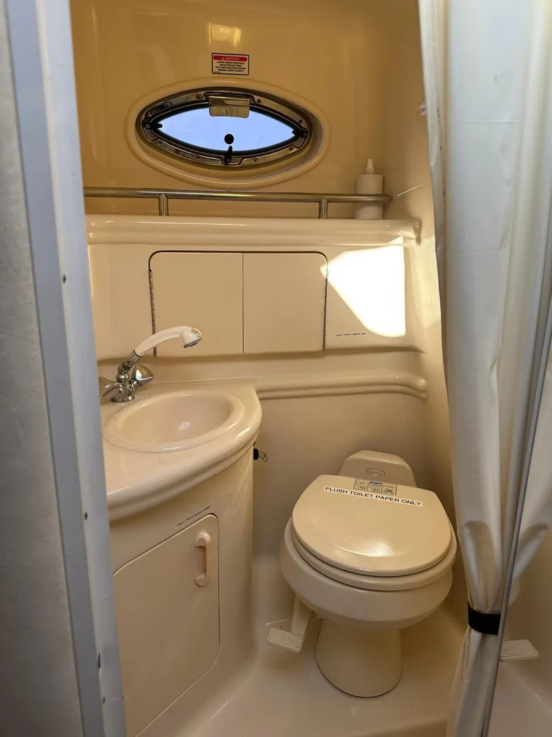 Slide: The Image of 2005 Sea Ray 280 Sundancer bathroom with sink, toilet, and porthole window. - 10