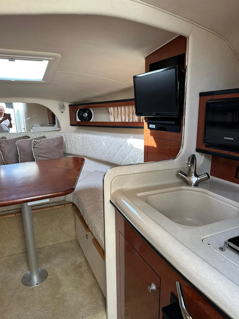 Slide: The Image of Interior of 2005 Sea Ray 280 Sundancer with kitchenette, seating, and TV. - 11