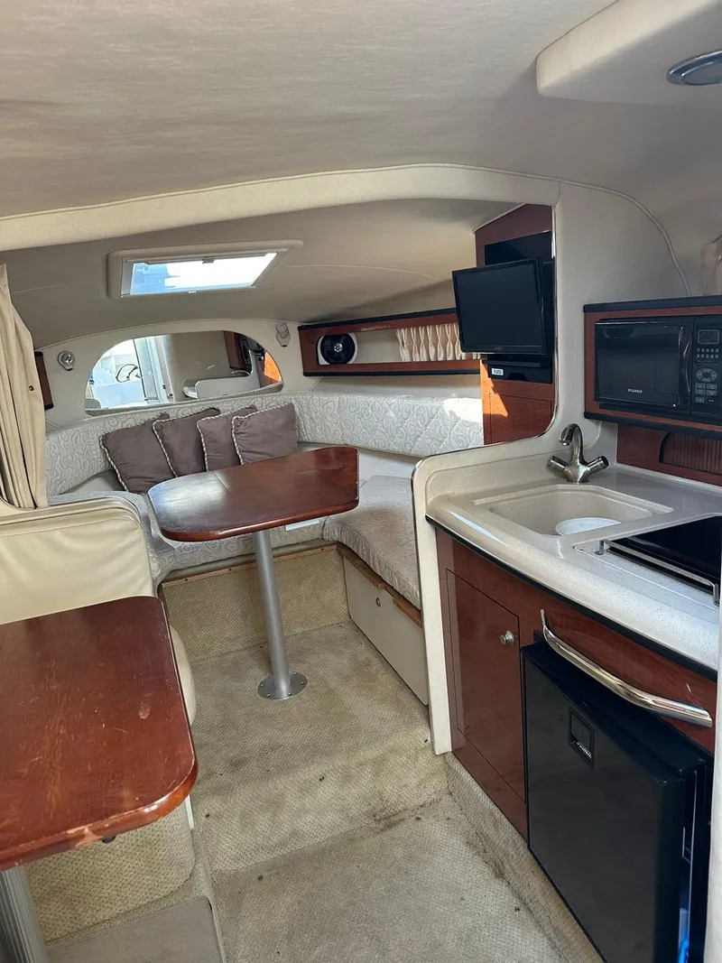 Slide: The Image of 2005 Sea Ray 280 Sundancer cabin interior with kitchenette, dining area, and seating. - 7