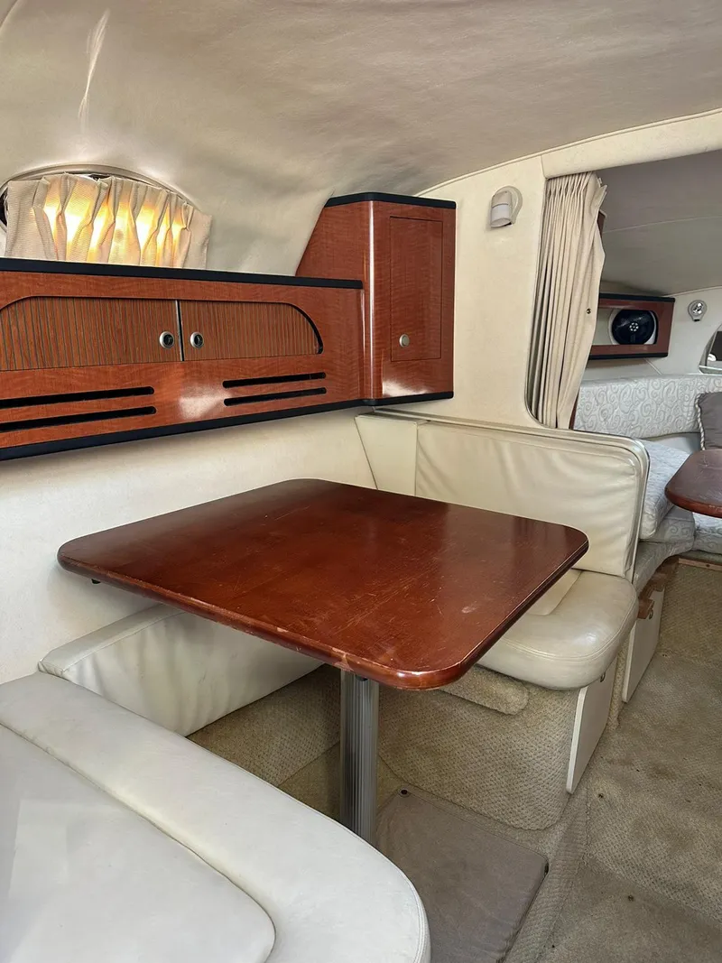 Slide: The Image of 2005 Sea Ray 280 Sundancer cabin interior with wooden table and cushioned seating. - 8