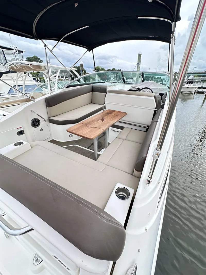 Slide: The Image of 2015 Sea Ray 260 Sundancer boat interior with seating and table, docked at marina. - 17
