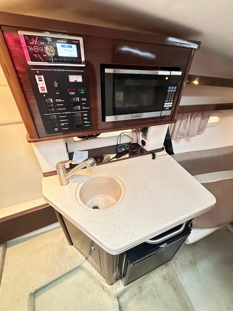 Slide: The Image of 2015 Sea Ray 260 Sundancer kitchenette with sink, microwave, and control panel. - 19