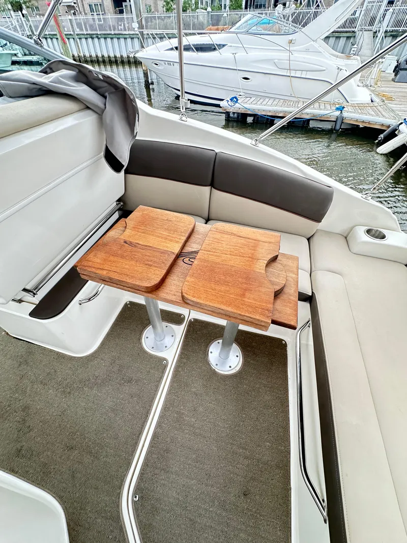 Slide: The Image of 2015 Sea Ray 260 Sundancer interior with wooden table and cushioned seating. - 5