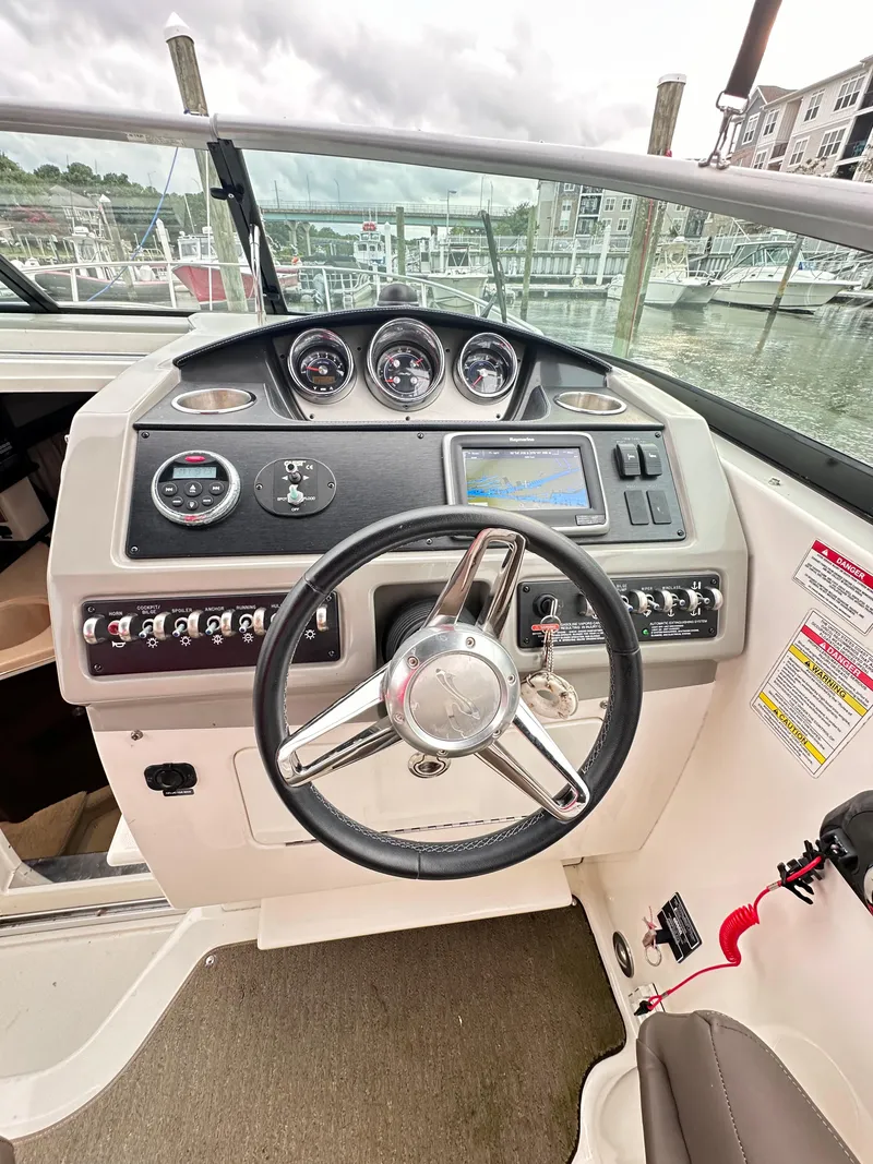 Slide: The Image of 2015 Sea Ray 260 Sundancer helm with steering wheel and control panel at marina. - 7