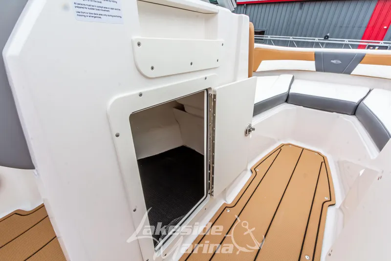 Slide: The Image of 2025 Chaparral 21 SSi boat interior storage compartment with open door, showcasing seating and flooring. - 33