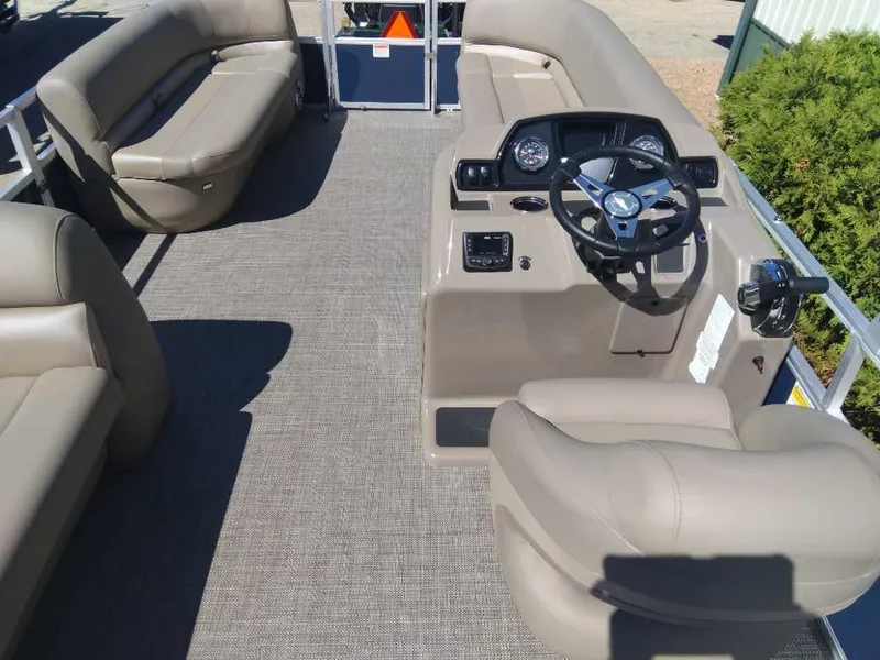 Slide: The Image of 2024 Ranger Reata 200C pontoon boat interior with beige seating and steering console. - 2
