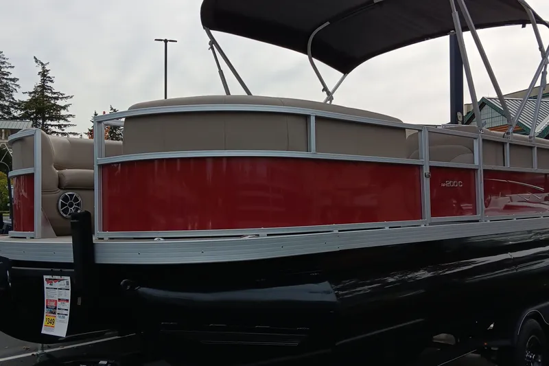 The Image of 2024 Ranger Reata 200C pontoon boat with red and beige design, parked outdoors. - 0