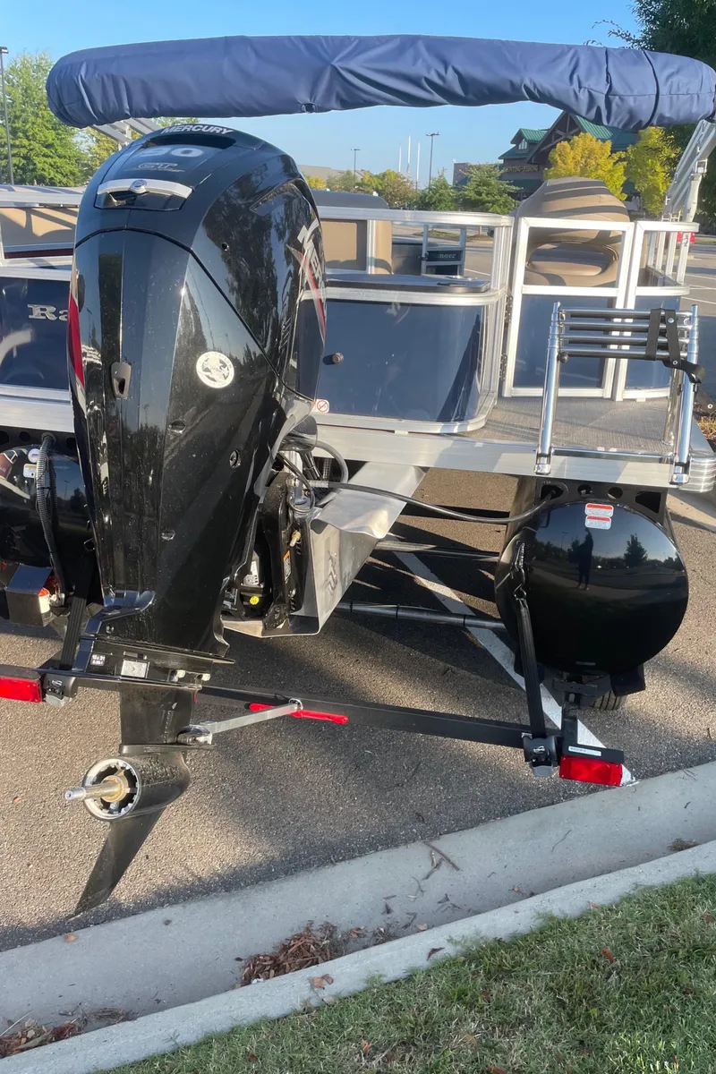 Slide: The Image of 2024 Ranger Reata 200F boat with outboard motor and canopy, parked on a trailer. - 7