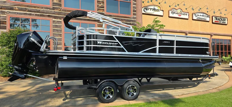 Slide: The Image of 2024 Ranger Reata 223C pontoon boat on trailer, black exterior, parked outdoors. - 1