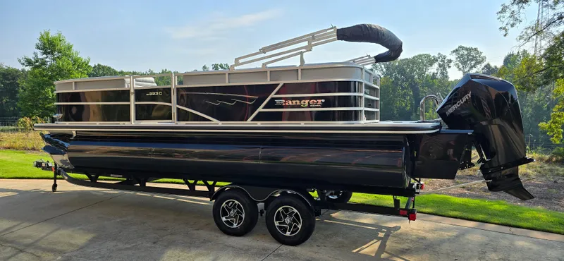Slide: The Image of 2024 Ranger Reata 223C pontoon boat on trailer, parked outdoors. - 3