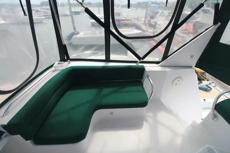 Slide: The Image of 1999 Mainship 31 Sedan Bridge interior with green seating and marina view. - 12
