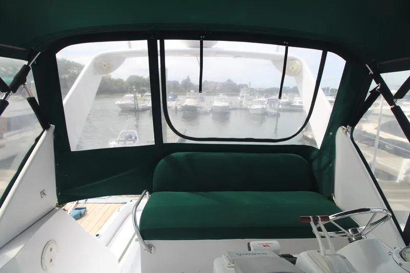 Slide: The Image of 1999 Mainship 31 Sedan Bridge interior with green seating, overlooking marina. - 14