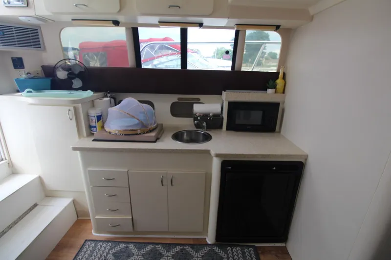 Slide: The Image of 1999 Mainship 31 Sedan Bridge interior kitchen with sink, microwave, and storage cabinets. - 24