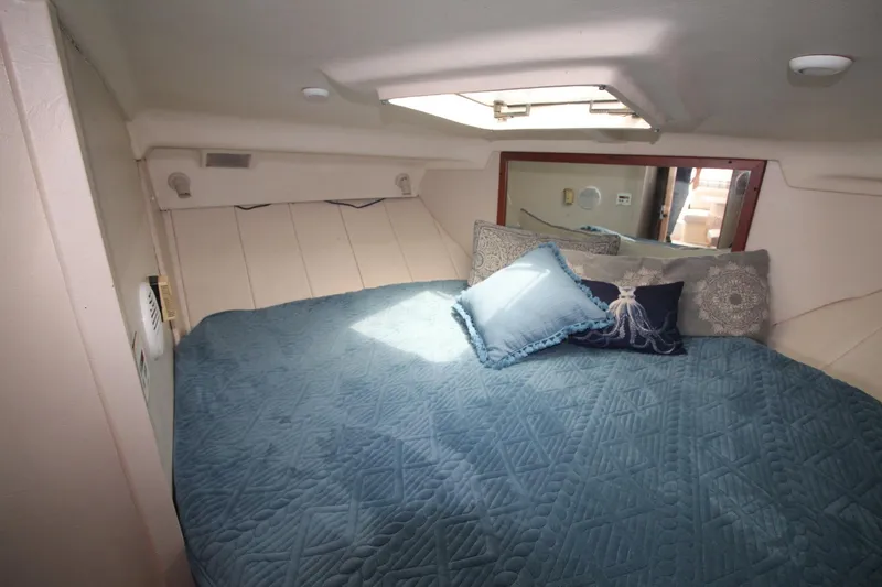 Slide: The Image of Cozy cabin interior of 1999 Mainship 31 Sedan Bridge with blue bedding and pillows. - 30
