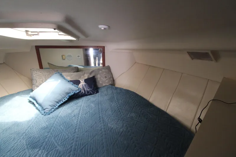 Slide: The Image of 1999 Mainship 31 Sedan Bridge cabin with blue bedding and decorative pillows. - 31