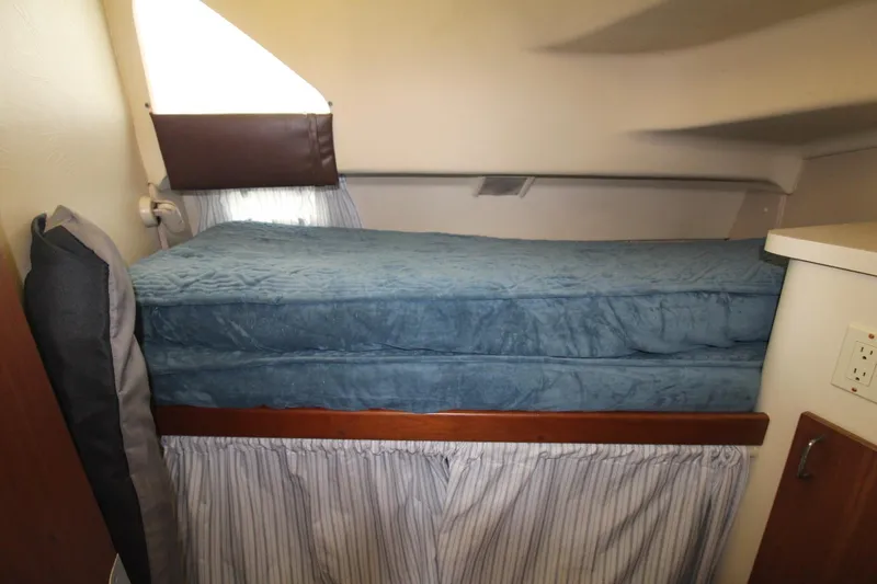 Slide: The Image of 1999 Mainship 31 Sedan Bridge interior with blue cushioned bed and striped curtain. - 36