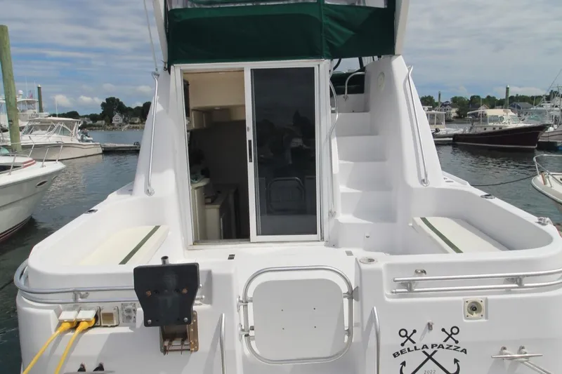 Slide: The Image of 1999 Mainship 31 Sedan Bridge yacht with green canopy, docked at marina. - 47