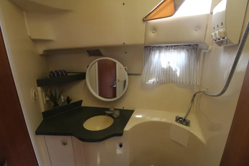Slide: The Image of 1999 Mainship 31 Sedan Bridge bathroom with sink, mirror, and shower area. - 48