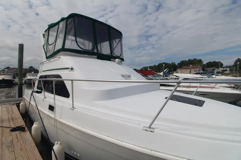 Slide: The Image of 1999 Mainship 31 Sedan Bridge boat docked at marina under cloudy sky. - 5