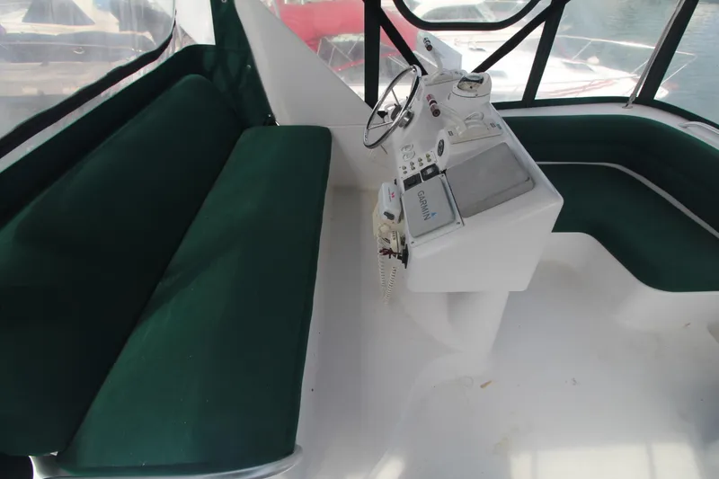 Slide: The Image of 1999 Mainship 31 Sedan Bridge interior with green seating and helm station. - 7